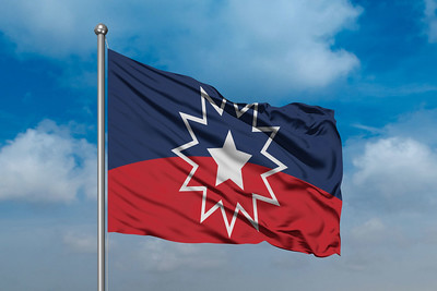 Juneteenth flag against a blue sky with light clouds