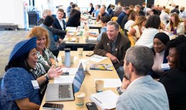 Large group of people talking while sitting at conference tables