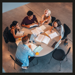 Photo of people sitting around a table with open books