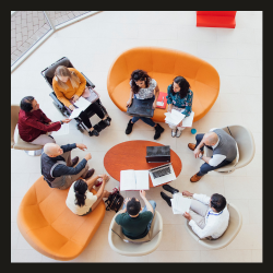 Photo with overhead view of people sitting in a circle with laptops