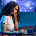 Photograph of student sitting at a table while using a laptop