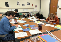 students sitting at table in the library working on papers