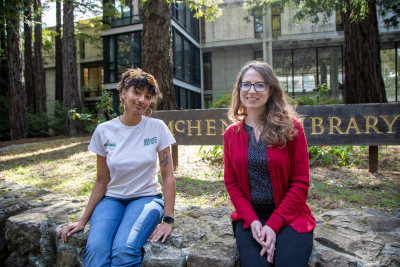 Jessica Waggoner and her student Kiara Winslow sitting in front of the McHenry Library sign