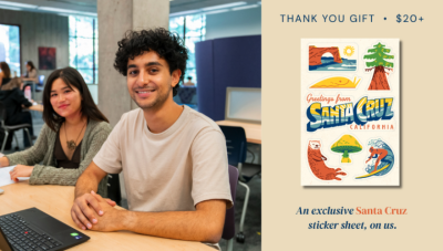 two students sitting at desk review rare book materials and a display of Santa Cruz stickers