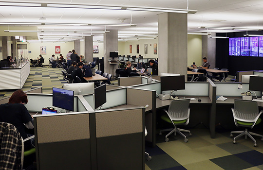 Photo showing a large visualization wall with chairs and tables in the foreground